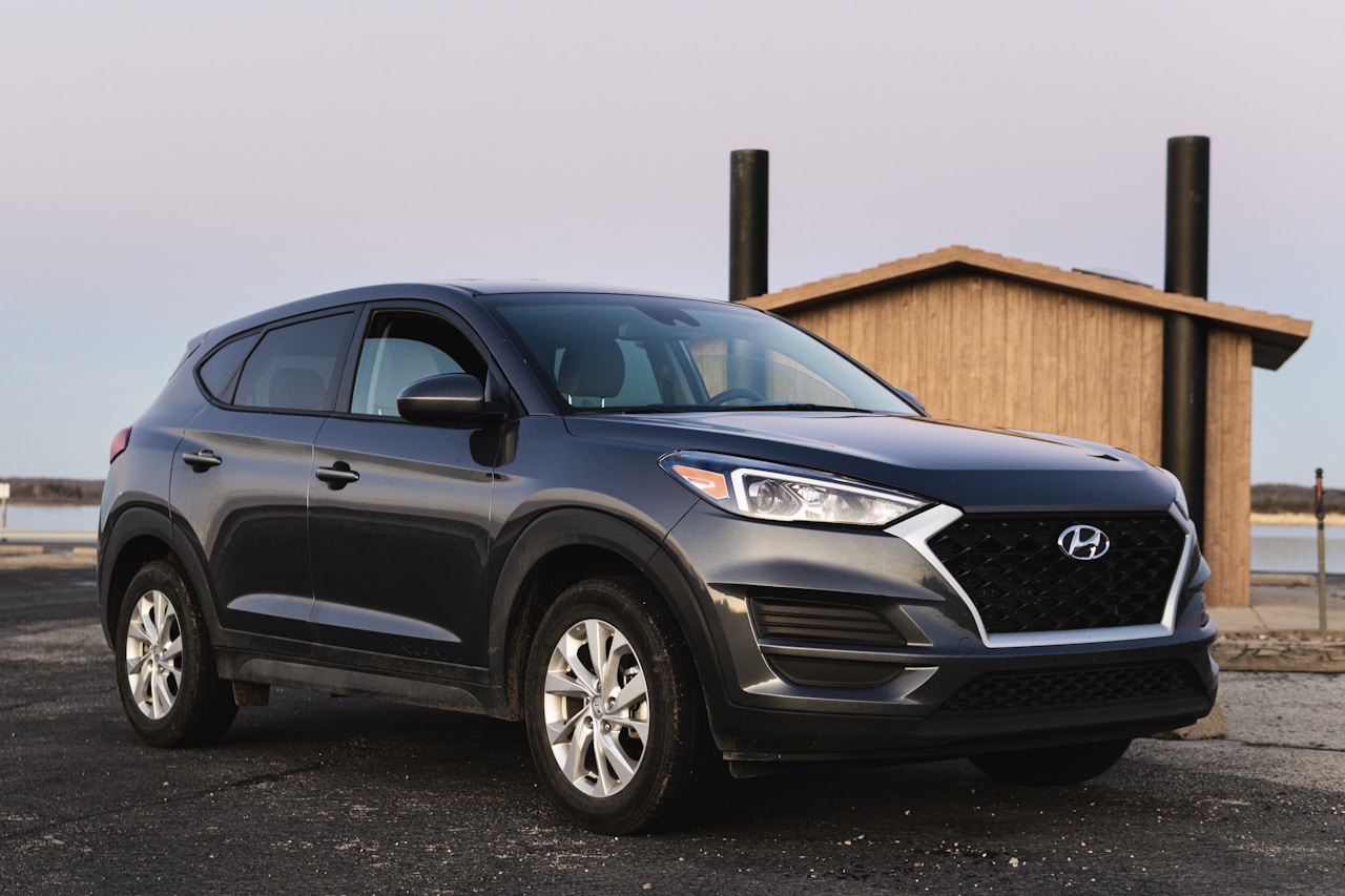 Hyundai Tucson negro aparcado junto a una casa de madera al atardecer
